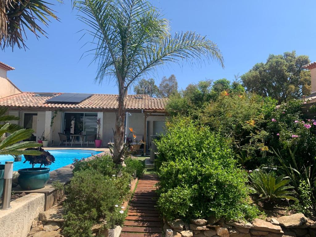 a house with a swimming pool and a palm tree at LA PASSIFLORE in La Londe-les-Maures