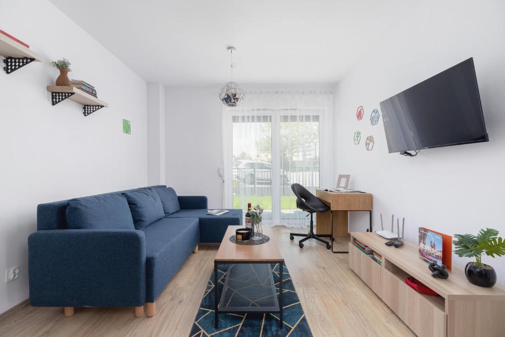 a living room with a blue couch and a tv at Family Apartment with Parking & Terrace by Renters in Kraków
