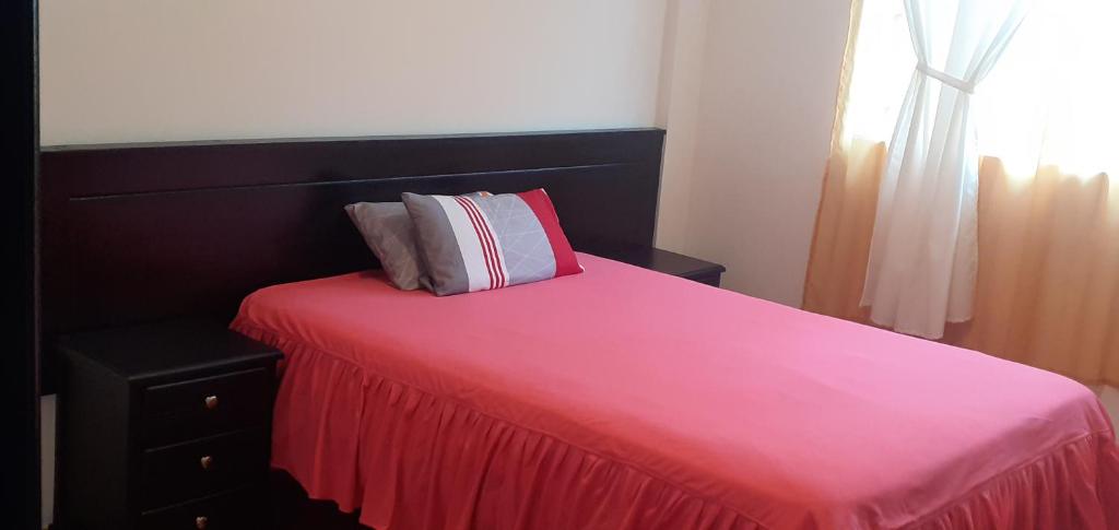 a bedroom with a pink bed with a red blanket at Casa campestre en las faldas del Taita Imbabura in San Juan de Ilumán