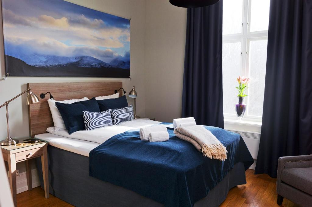 a bedroom with a bed with blue sheets and a painting at Frogner House - Slottsparken in Oslo