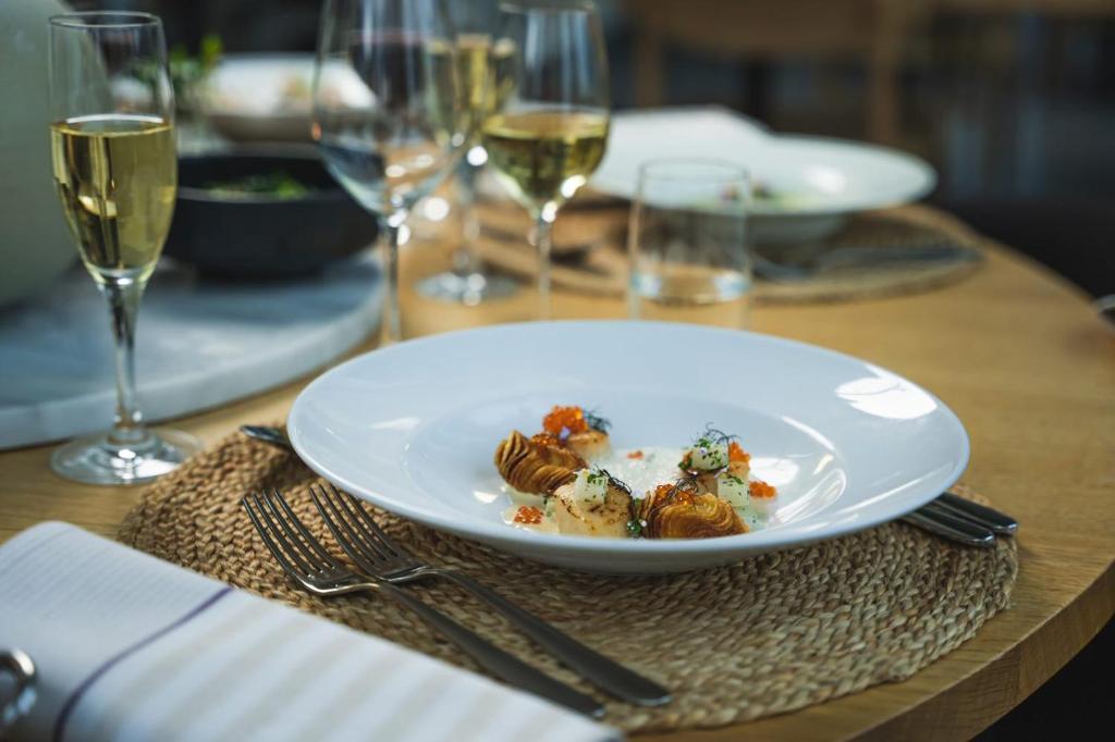 een bord eten op een tafel met wijnglazen bij Skepparholmen Nacka in Nacka