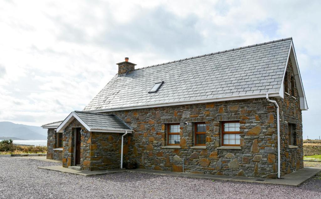 a stone house with a slate roof at Beautiful stone cottage with sea views in Sneem