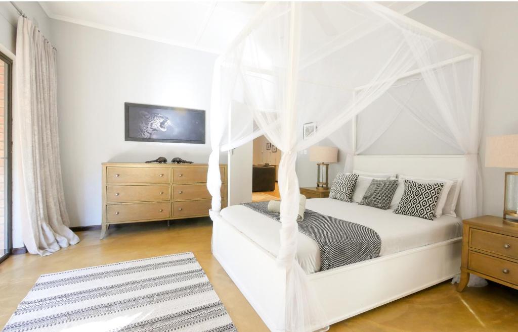 a bedroom with a white bed with a canopy at Victoria Falls Holiday Home in Victoria Falls