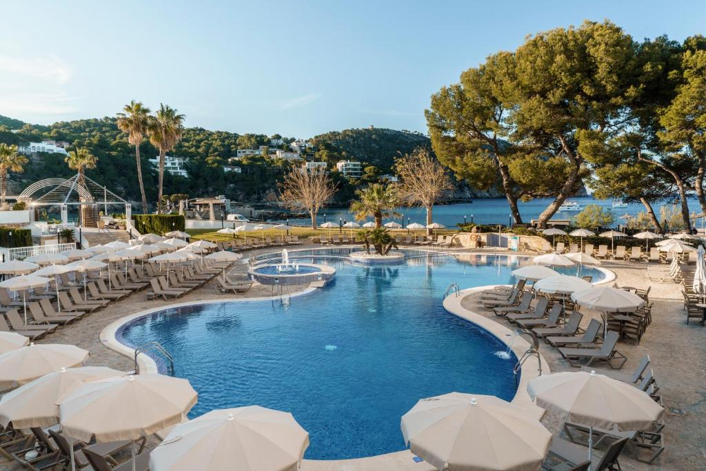 a pool with white umbrellas and tables and chairs at Alua Gran Camp de Mar in Camp de Mar
