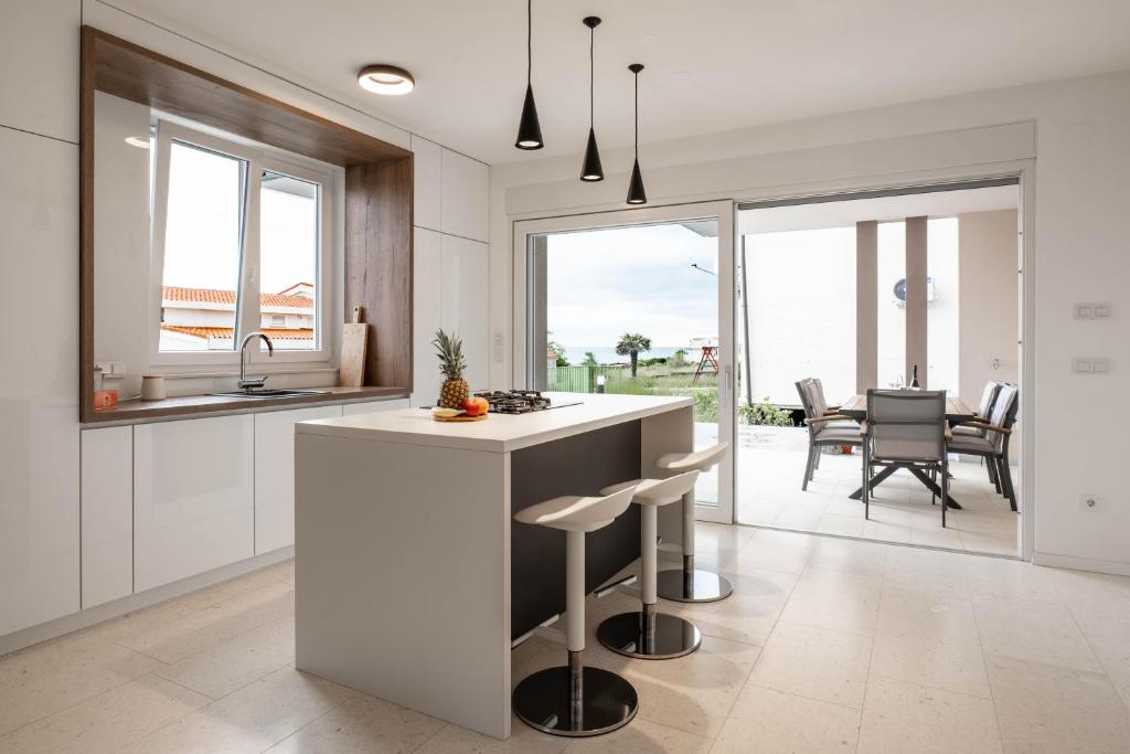 a kitchen with white cabinets and a island with bar stools at Apartment Dubravka in Povljana