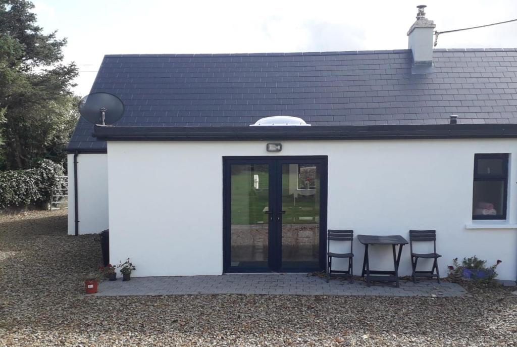 a white building with two chairs and a table at Peg and Barrys Cottage near Fenit in Fenit