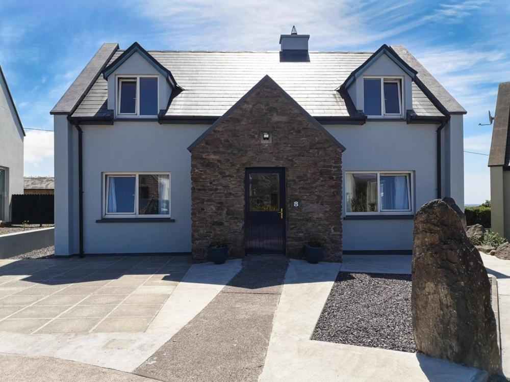 a white house with blue windows and a rock at 4 bedroomed holiday home close to the beach in Waterville
