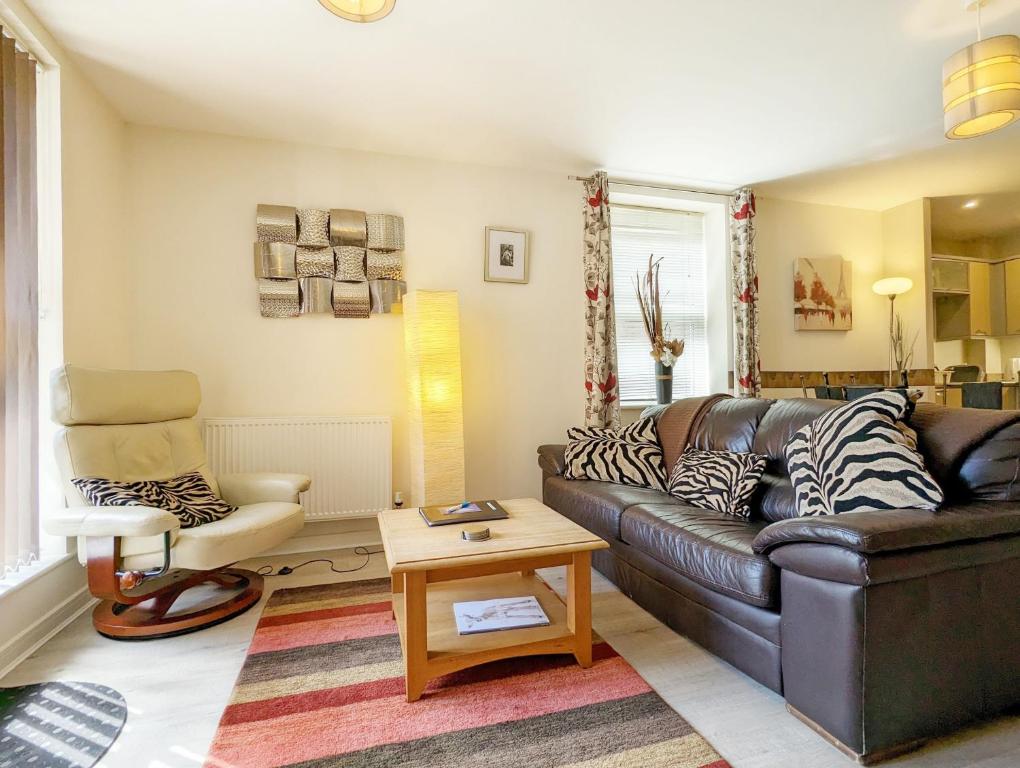 a living room with a leather couch and a chair at Roman Quarter , Chichester in Chichester