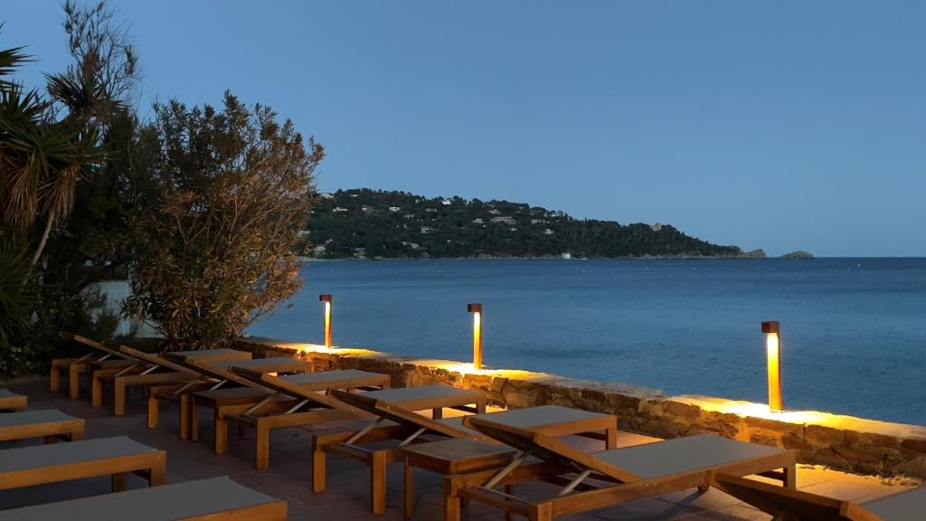 a row of tables and chairs next to the water at Surplage Hotel Cavalière in Le Lavandou
