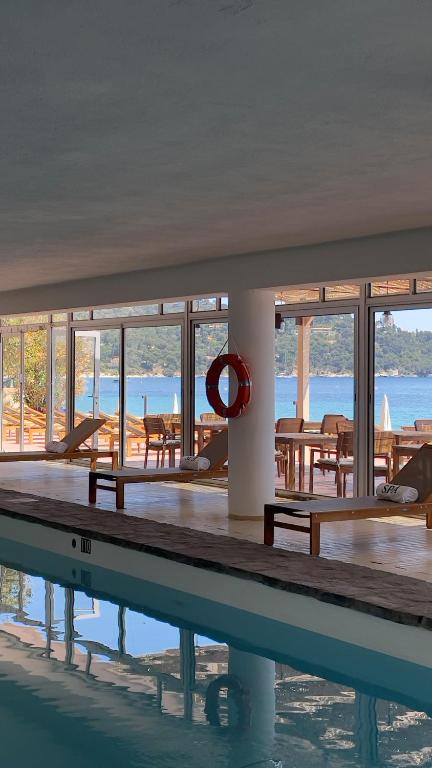 a swimming pool with tables and chairs in a building at Surplage Hotel Cavalière in Le Lavandou