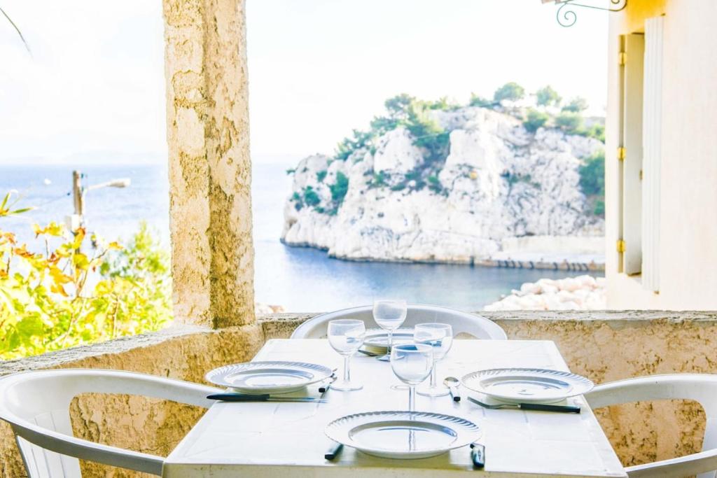 una mesa con copas de vino y vistas al océano en Pieds dans l'eau - Terrasse vue mer 2 chambres, en Le Rove