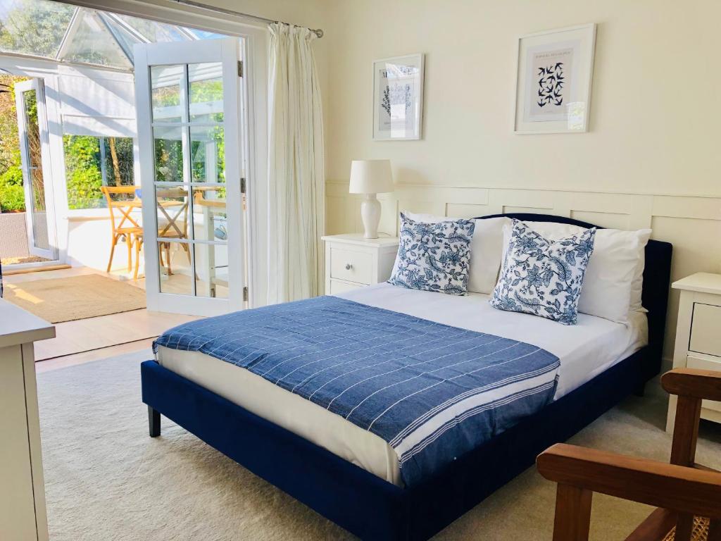 a bedroom with a bed with blue and white pillows at Secluded Spacious Garden Suite in Chichester