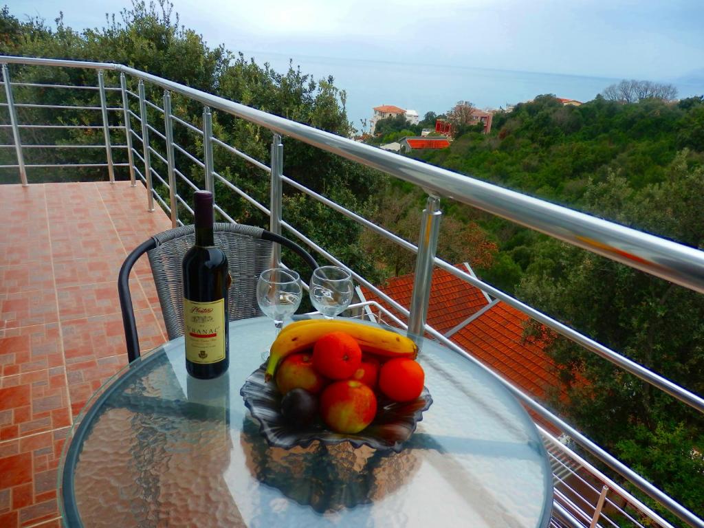 - une table en verre avec une bouteille de vin et des fruits sur le balcon dans l'établissement Apartments Vladilena, à Utjeha-Bušat