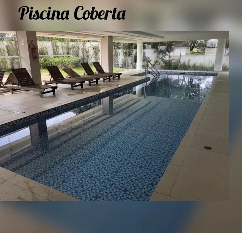 een zwembad in een gebouw met ligstoelen ernaast bij Studio Completo Cotia Granja Vianna 417 in Cotia