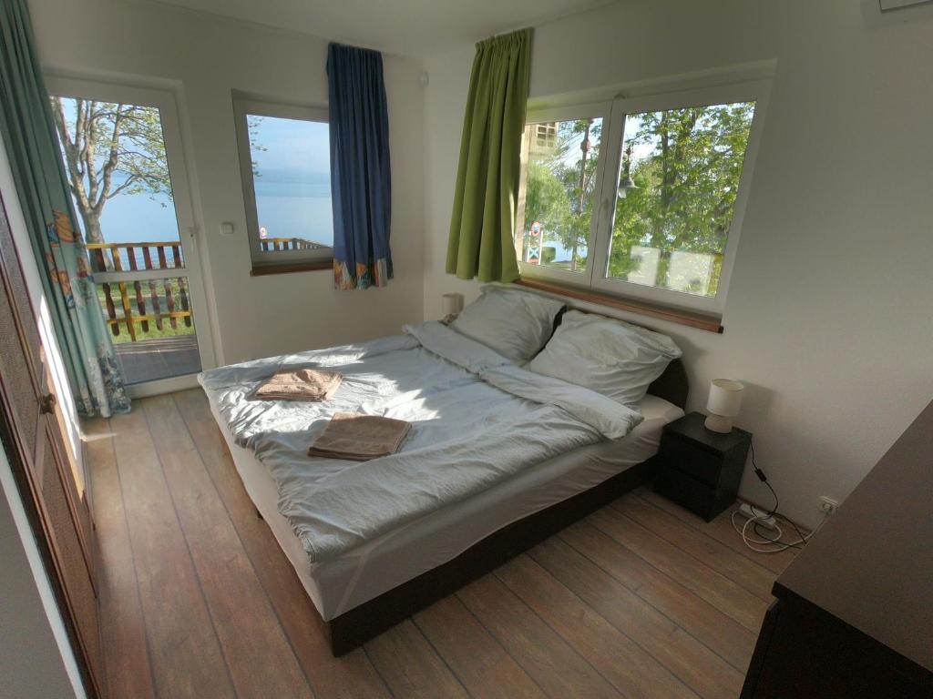 ein kleines Bett in einem Zimmer mit zwei Fenstern in der Unterkunft Pillangó Vendégház in Balatonboglár