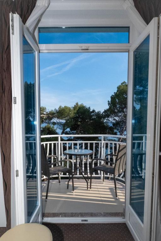 a glass door leading to a balcony with a table and chairs at Hotel Bor in Krk