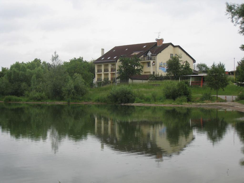 a house sitting next to a large body of water at Penzión Normandia in Nitrianske Rudno