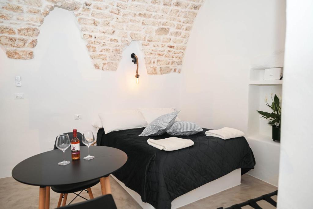 Habitación pequeña con cama y mesa con copas de vino en CASA FLAMI' 4 en Ostuni