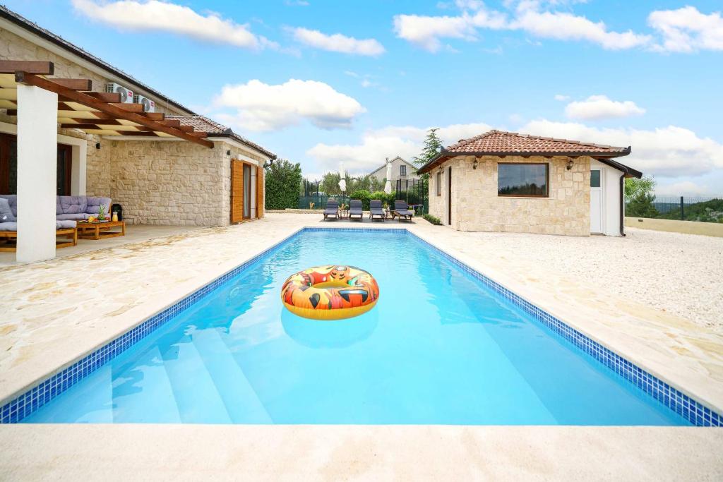 a swimming pool with a pool noodle in front of a house at Villa Lucia in Skradin