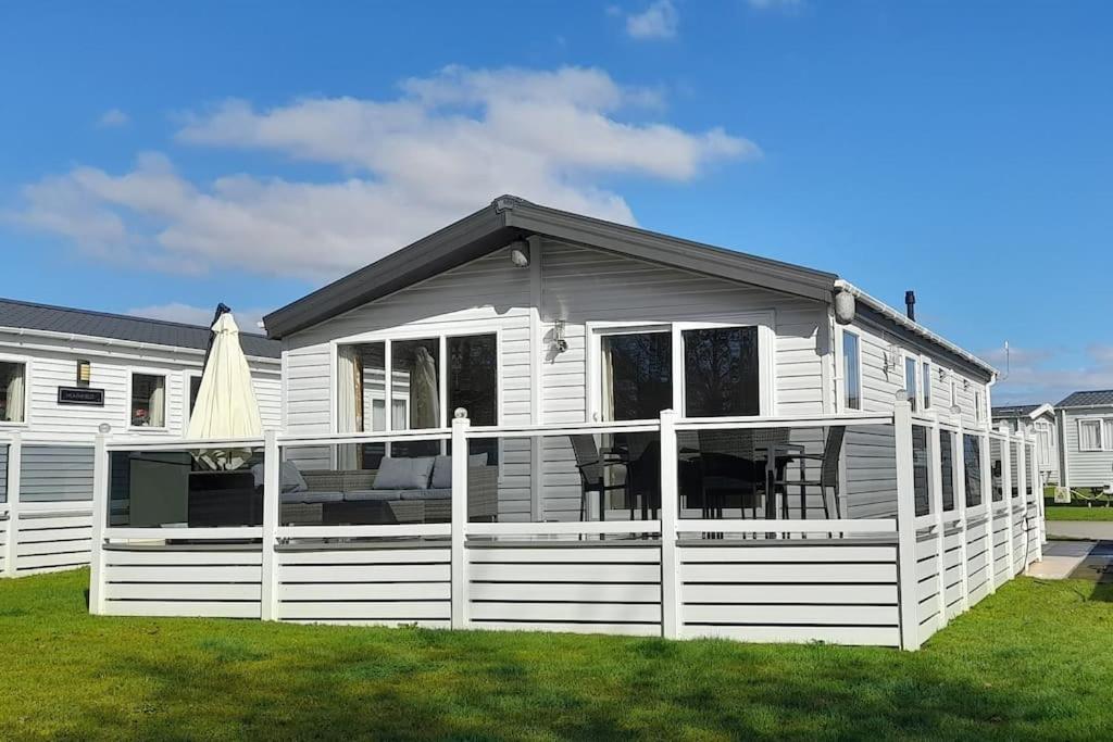 a white house with a porch and a white fence at Platinum lodge on Carlton Meres holiday Park in Rendham