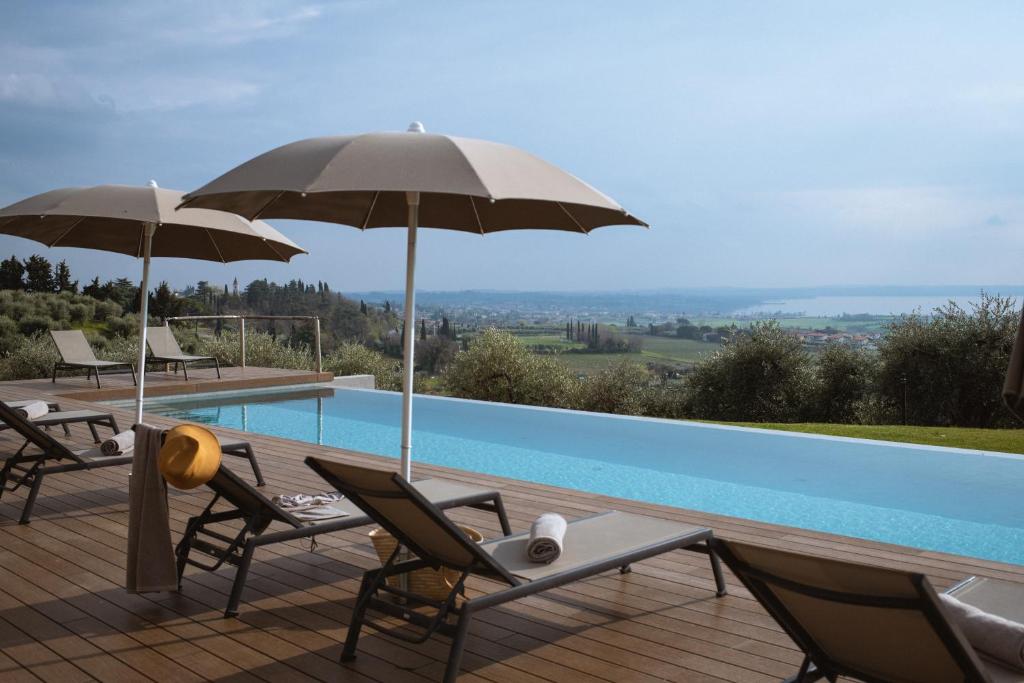 una piscina con 2 sillas y una sombrilla en Villa Cavaion, en Cavaion Veronese