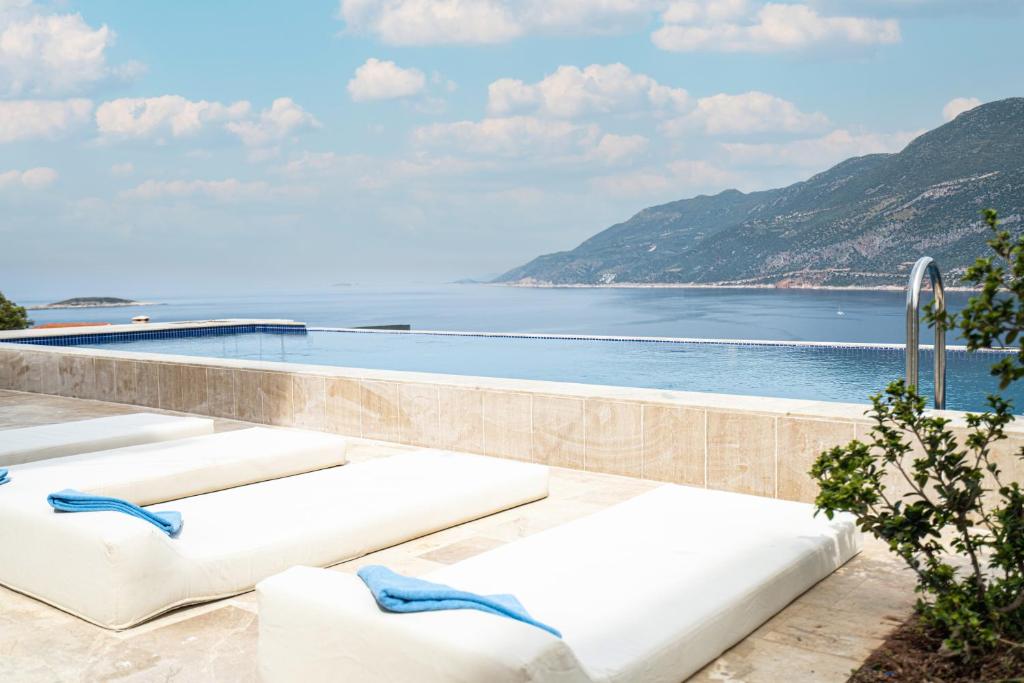 een zwembad met witte ligstoelen naast het water bij Gumus Peninsula Hotel in Kas
