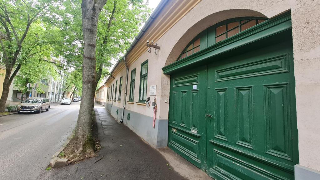 una porta verde del garage sul lato di un edificio di Belvárosi BástyaVár Apartman a Gyula