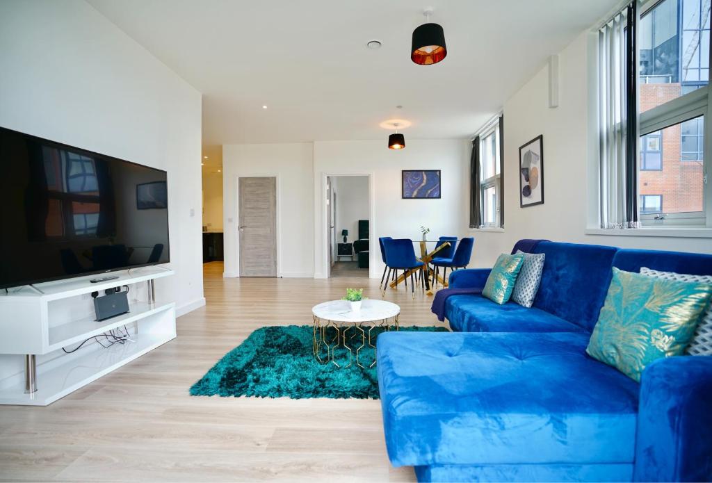 a living room with a blue couch and a tv at Large Balcony Apartment with City View by DH ApartHotels in Peterborough