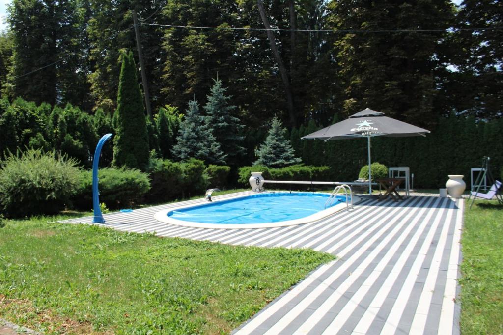 a swimming pool with an umbrella next to a garden at Villa Donata in Sarajevo