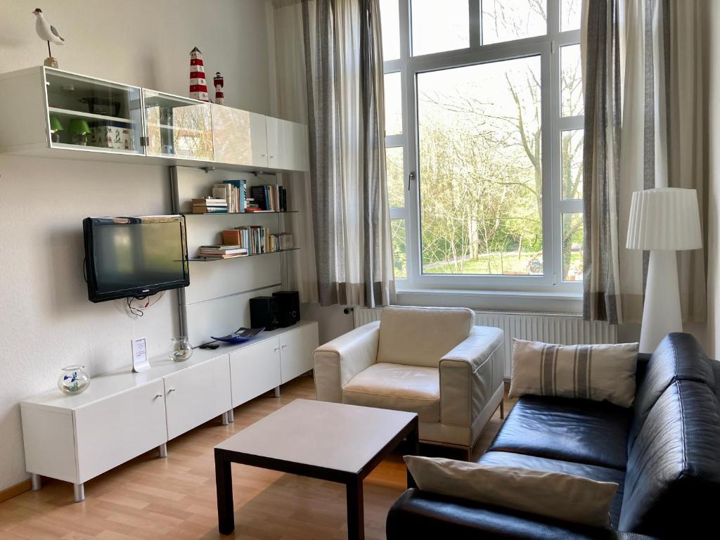 - un salon avec un canapé et une télévision dans l'établissement Residenz am Rosengarten 16, à Wangerooge