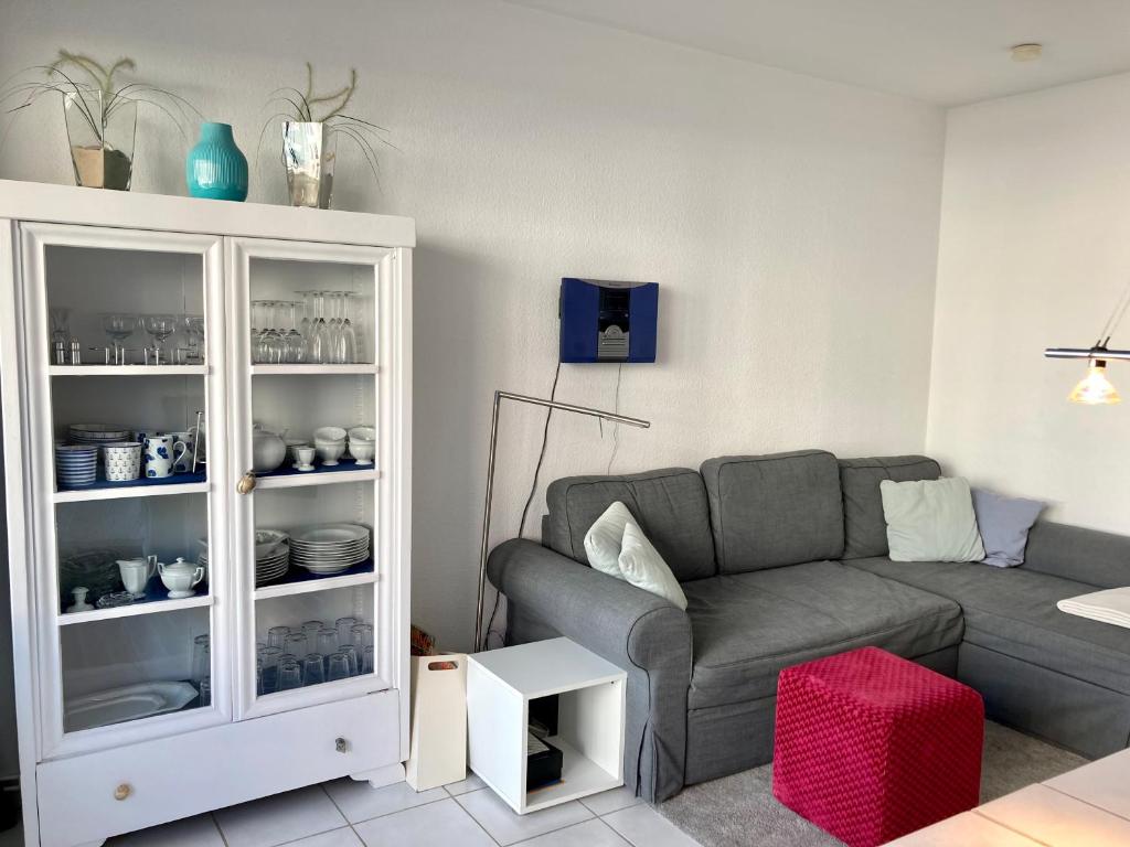 ein Wohnzimmer mit einem grauen Sofa und einem weißen Schrank in der Unterkunft Haus Seeluft Whg 11 in Wangerooge