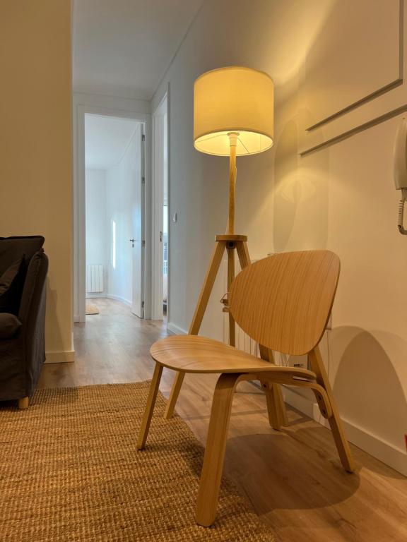 a lamp and a wooden chair in a living room at Braga Centro, Totalmente remodelado em 2023! in Braga