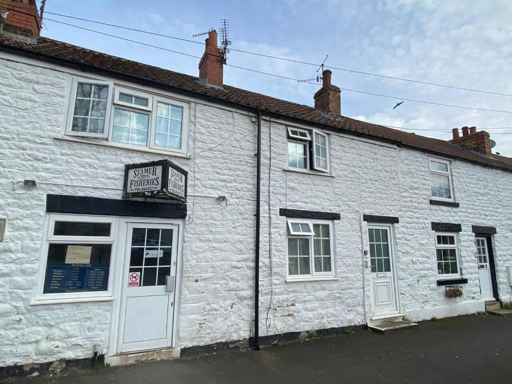 a white brick building with a sign on it at 3 Bedroom Cottage Sleeps 5 village location in Scarborough