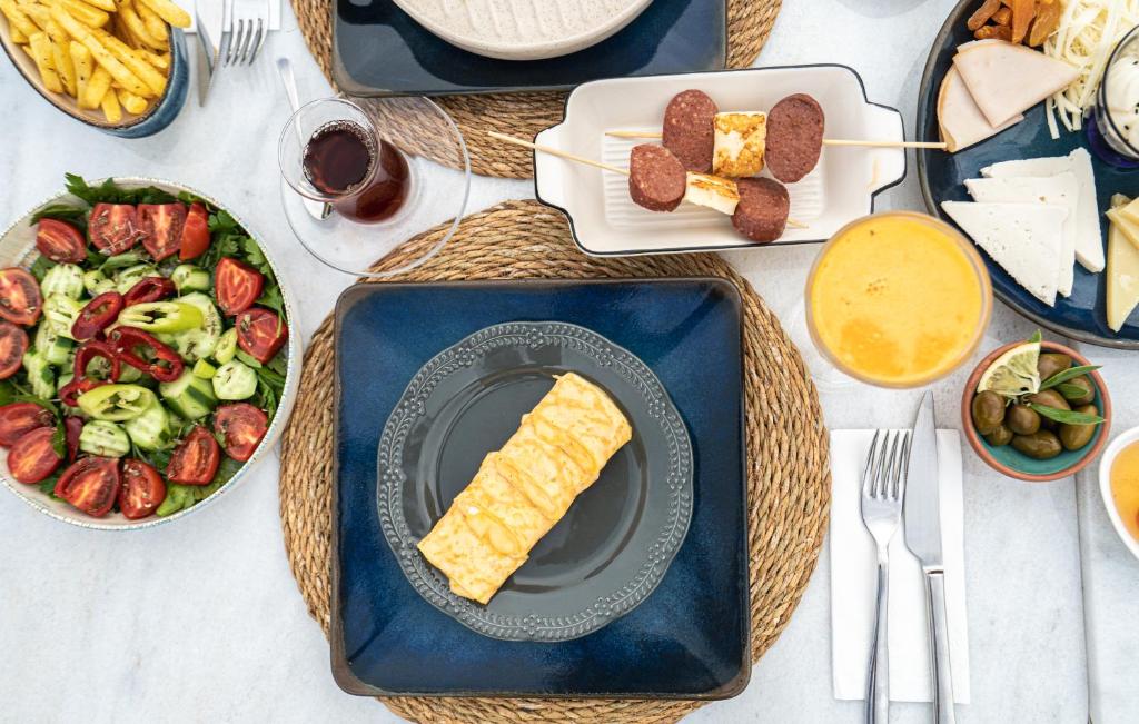 a table with plates of food and a salad and meats at Gümüş Yazar Hotel in Kaş