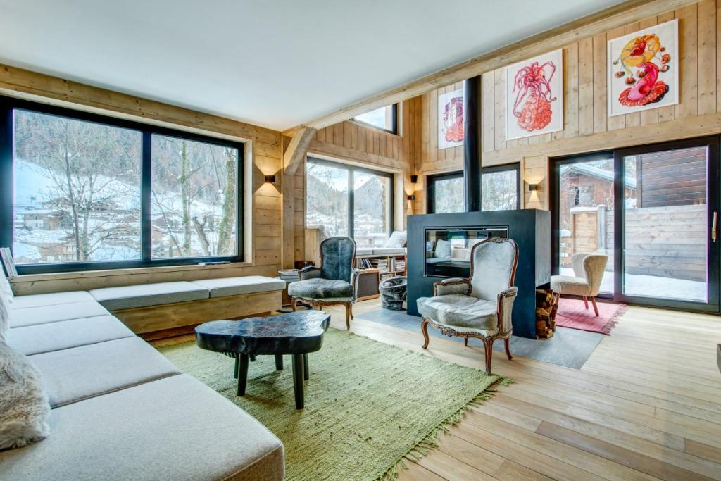 a living room with a couch and chairs and windows at Chalet Nosefosa - Magnifique chalet neuf avec piscine intérieure, pour 10 personnes in Morzine