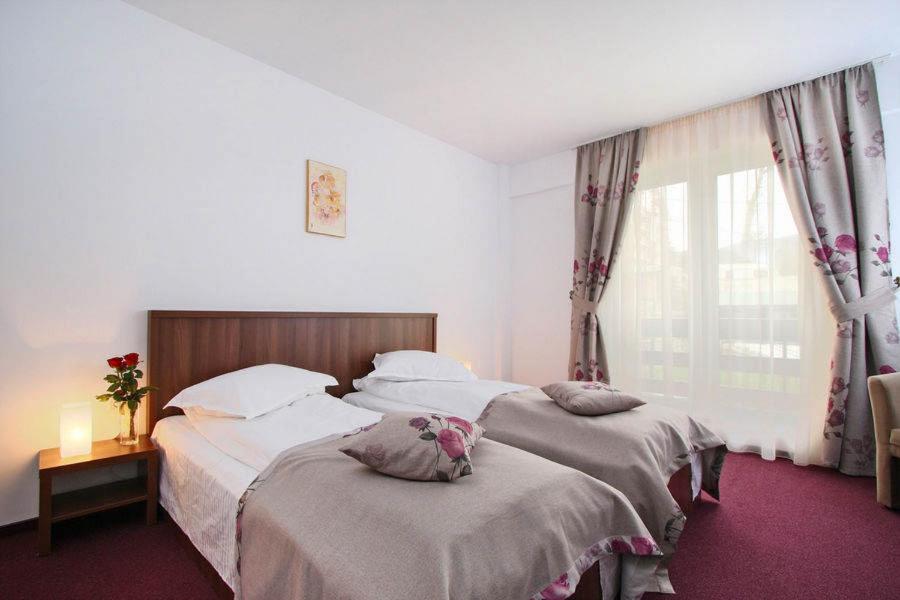een slaapkamer met twee bedden en een raam bij Hotel Domnitei in Călimăneşti