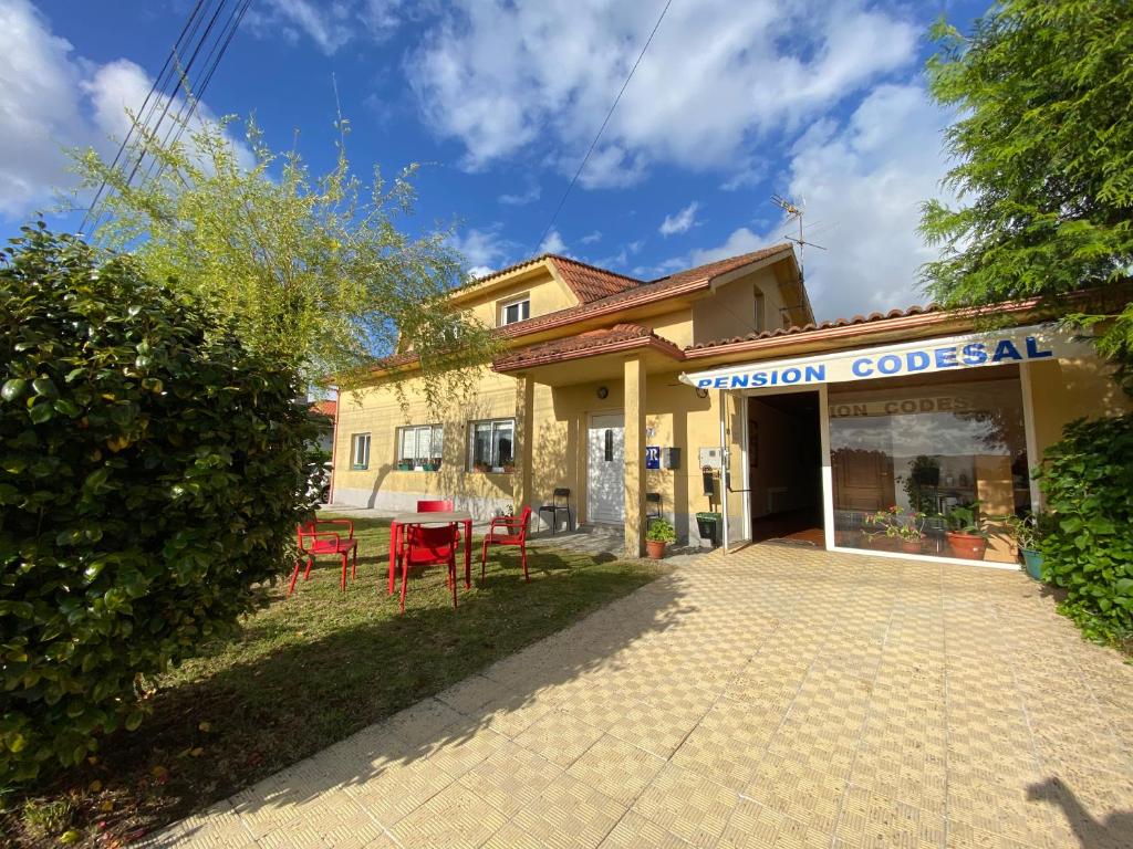 ein Gebäude mit einem Tisch und Stühlen davor in der Unterkunft Pensión Codesal in O Pedrouzo