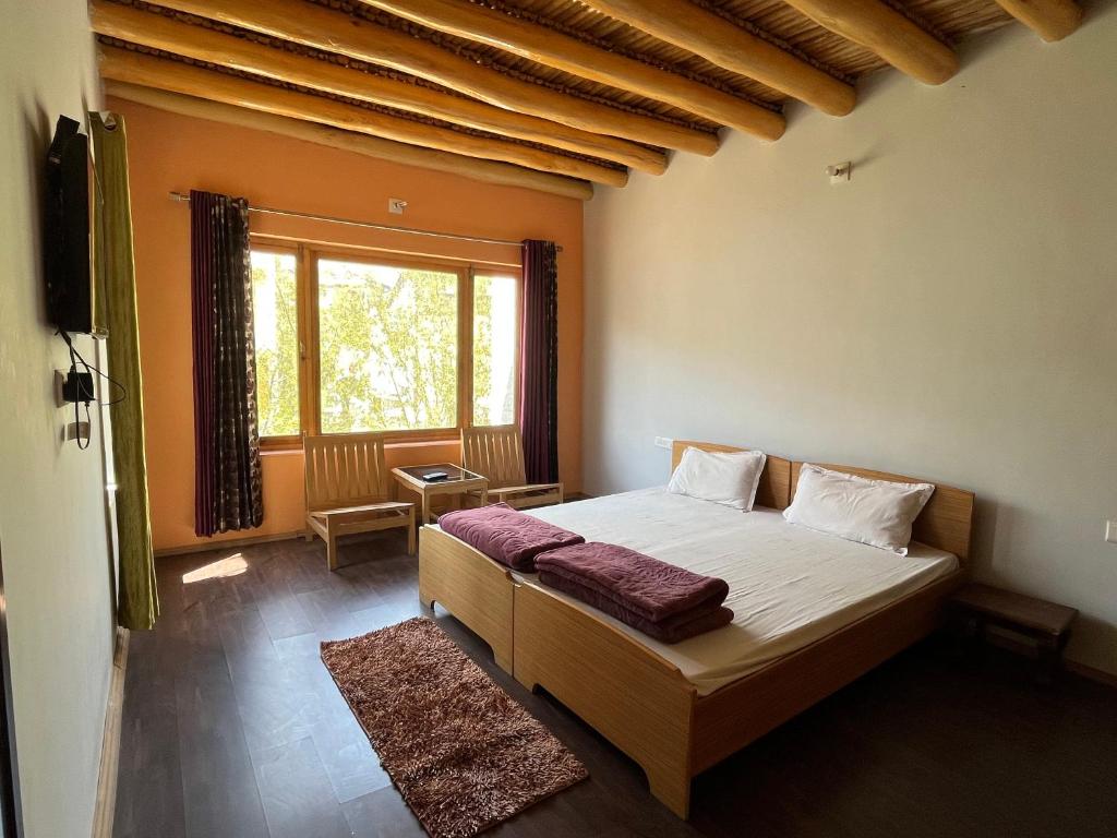 a bedroom with a bed and a large window at Chakzot garden house in Leh