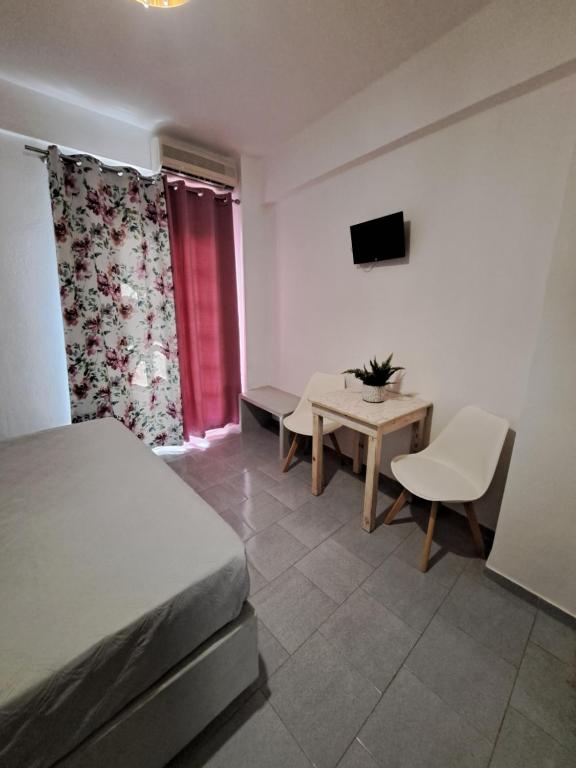 a bedroom with a bed and a table and a tv at Studios Irineos in Perissa