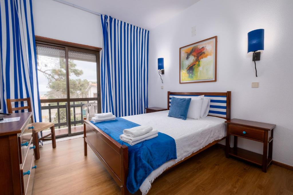 a bedroom with a bed with blue sheets and a window at Hotel Verde Pinho Bed&Breakfast in São Pedro de Moel