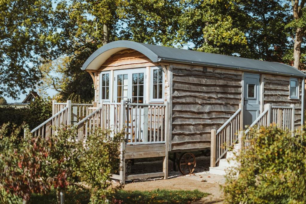 a wooden cabin with a porch and a white fence at Hornington Manor Luxury Shepherd Huts in York