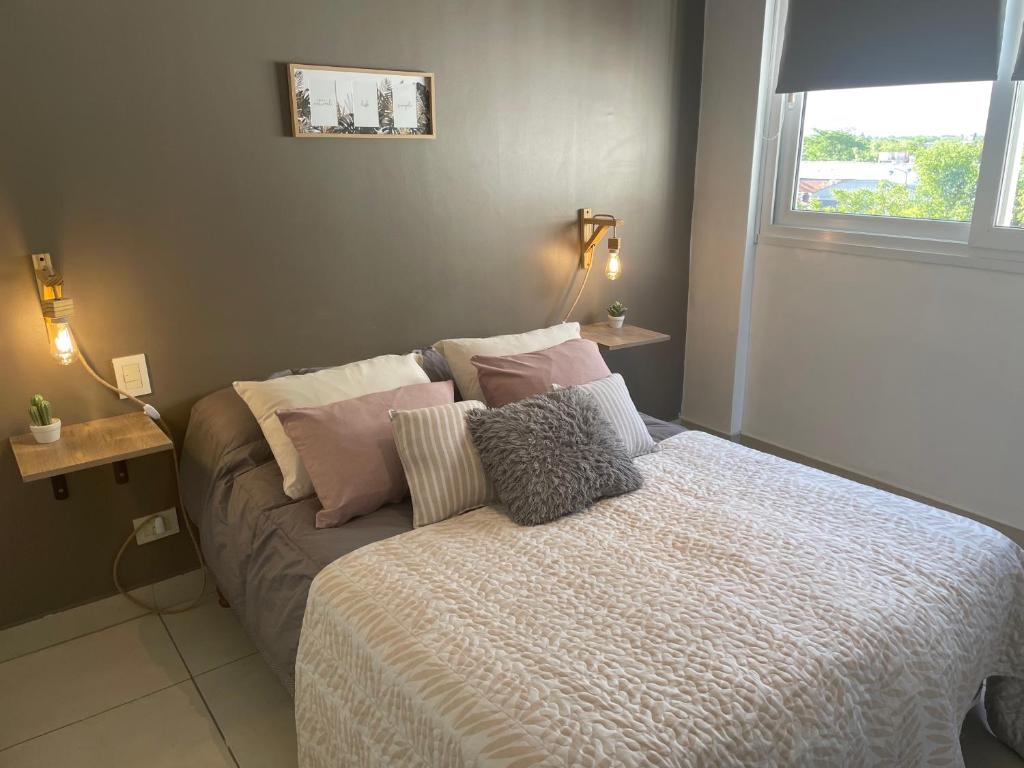 ein Schlafzimmer mit einem Bett mit Kissen und einem Fenster in der Unterkunft Andes Apartments Bandera in Mendoza