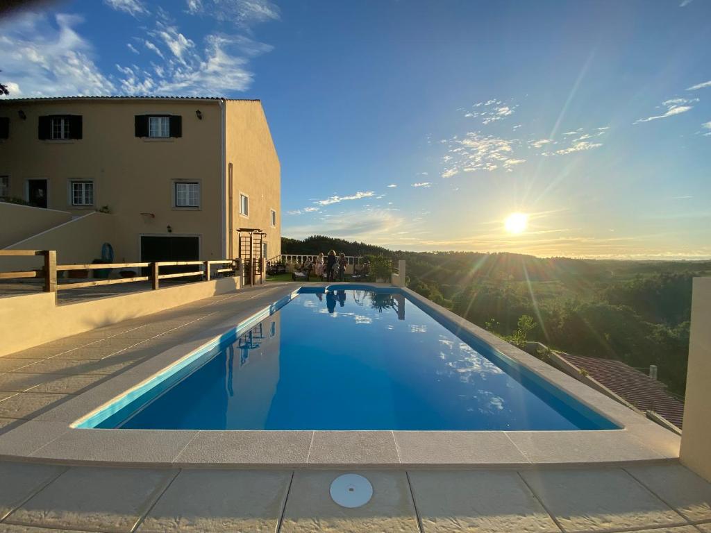 - une piscine sur le côté d'un immeuble avec vue sur le coucher du soleil dans l'établissement Terra Luso Proche De Montejunto, à Cadaval