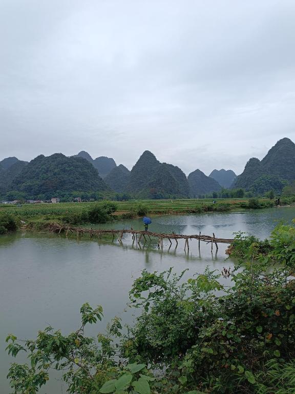 a river with a bunch of mountains in the background at An Homestay & Hostel Motorbikes & Tours in Cao Bằng