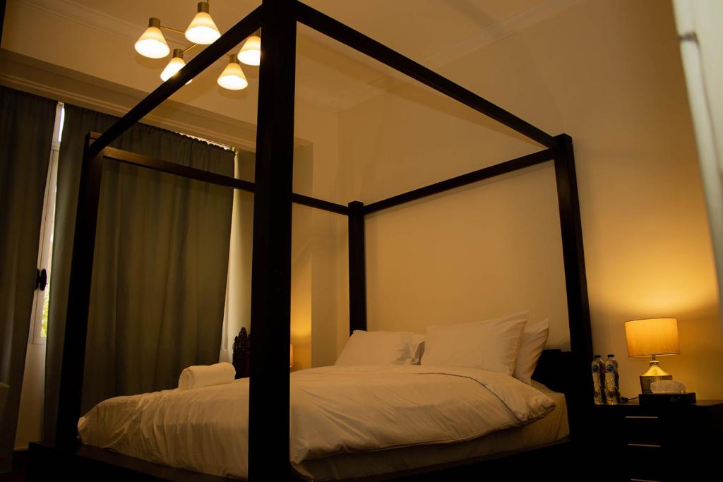 "Chez Riche" Luxury serviced apartment 12 في القاهرة: غرفة نوم مع سرير المظلة مع الوسائد البيضاء