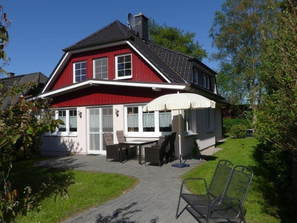 a red and white house with a table and an umbrella at Haus Marleen EG, FW 1 in Zingst