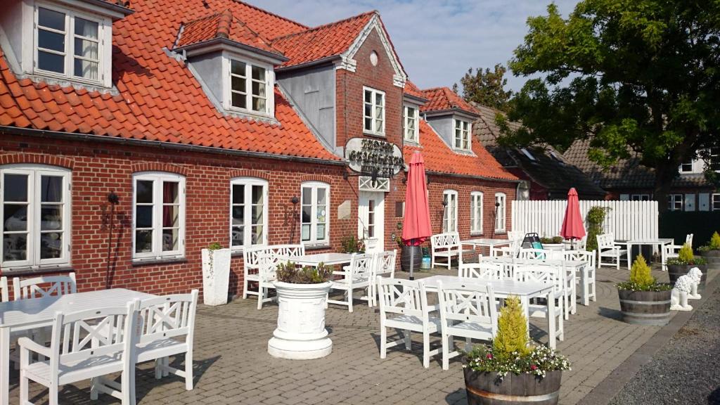 a group of white tables and chairs in front of a building at Rudbøl Grænsekro in Rudbøl