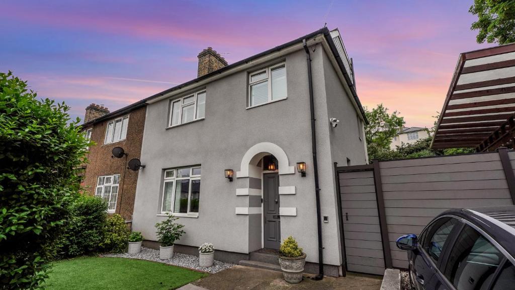 a gray house with a door in a yard at Cosy Luxurious Family Home in London