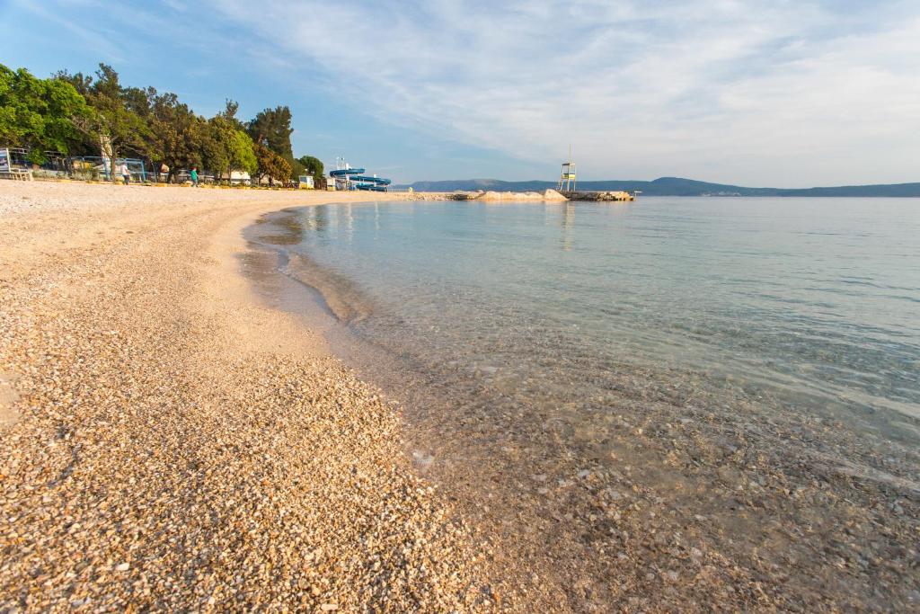 a sandy beach with a lighthouse in the water at Apartments Adriatic in Selce