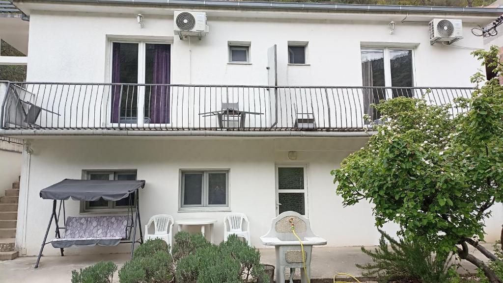 ein weißes Gebäude mit einem Balkon mit Stühlen und einem Tisch in der Unterkunft Apartmani Stolac in Stolac